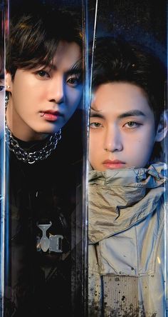 two young men standing next to each other in front of a glass wall with chains on it