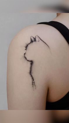 a cat tattoo on the back of a woman's shoulder