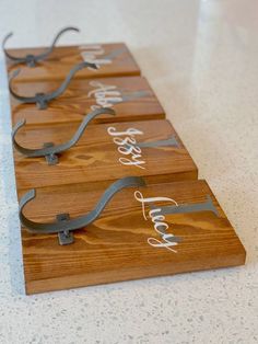 four wooden plaques with metal handles on a counter top, each displaying the names of different people