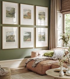 a living room with green walls and pictures on the wall above the couch, along with vases filled with flowers