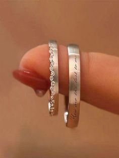 two silver rings with diamonds on them are held in someone's hand and the other is