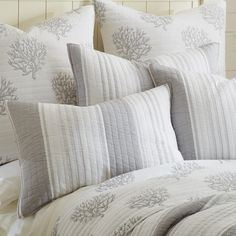 a bed with white and gray pillows on top of it