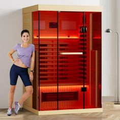 a woman standing next to an infrared sauna