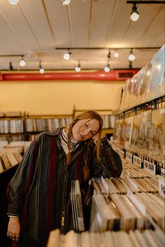 a woman standing in front of a shelf filled with cds