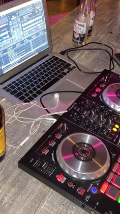 a laptop computer sitting on top of a table next to two decks of dj equipment