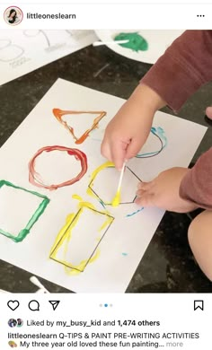 a child is drawing with colored crayons on the paper and holding a toothpick