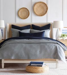 a bed with two wicker baskets on the wall above it and blue linens