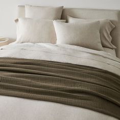 an unmade bed with white linens and pillows