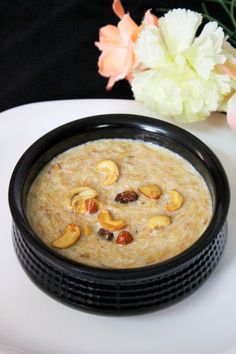 there is a bowl of soup on the plate with flowers in the vase behind it