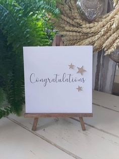 congratulations card on an easel with greenery in the background