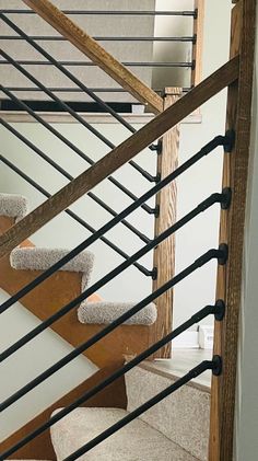 a cat sitting on top of a carpeted stair case next to a wooden banister