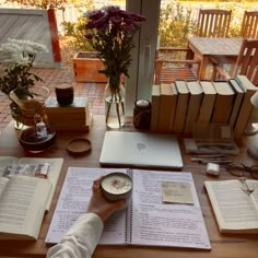 a person is sitting at a table with books and an open book on top of it