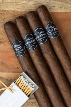 four cigars are sitting next to each other on a wooden table with labels and matches