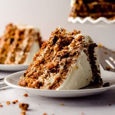 a slice of carrot cake on a plate with a fork next to it and another piece in the background