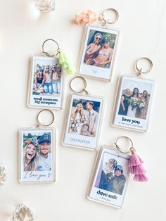 four different key chains with pictures hanging from them on a white table next to crystal beads