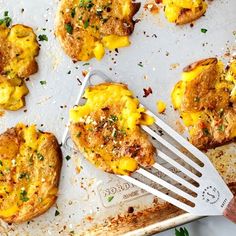 some food is laying out on a baking sheet with a fork in it and there are several pieces of bread that have been topped with cheese