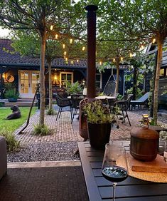 an outdoor patio with lights strung from the ceiling and potted plants on the table