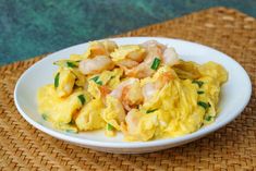 a white plate topped with scrambled eggs and shrimp