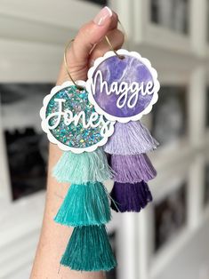 a person holding up some tassels with the words imagine on them in purple, green and blue