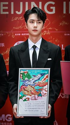 a man in a suit and tie holding up a framed poster with writing on it