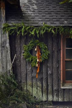 a wreath is hanging on the side of a wooden building with ivy growing around it