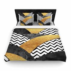 a bed with black and gold comforter covers on top of each other, in front of a white background