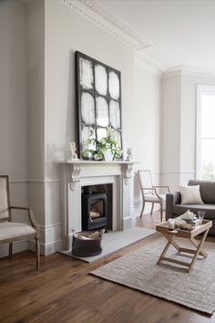 a living room filled with furniture and a fire place next to a window on top of a hard wood floor