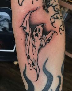 a person with a tattoo on their arm that has a ghost and a bird above it