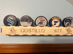 a wooden sign that says costillo with six different types of buttons on it hanging from the wall