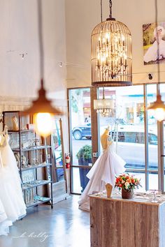 wedding gowns are on display in the window of a bridal shop with chandeliers hanging from the ceiling