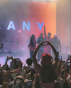 a group of people standing on top of a stage with their hands in the air