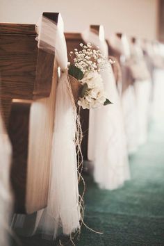 flowers are tied to the pews at a wedding ceremony in white tulle and burlock