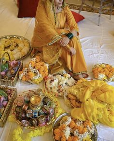 a woman sitting on top of a bed next to baskets filled with flowers and food