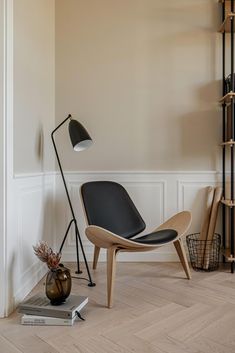 an empty room with a chair, lamp and bookshelf on the floor in front of it