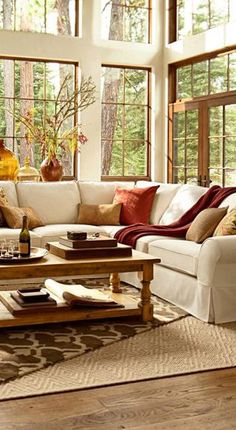 a living room filled with lots of furniture and large windows in the wall behind it