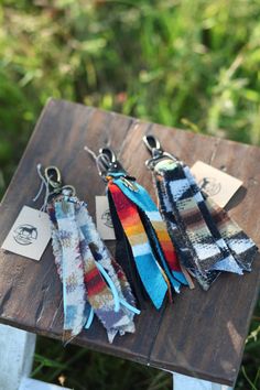 four different colored ties are on a wooden table outside with grass in the back ground