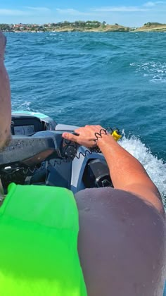 a man riding on the back of a boat while holding onto something in his hand