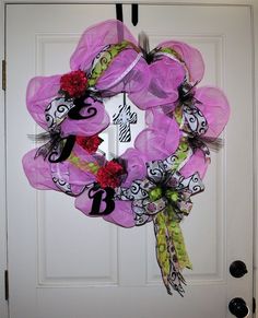 a purple wreath with black and white letters on the front door is decorated with flowers