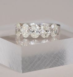 a five stone diamond ring sitting on top of a white box