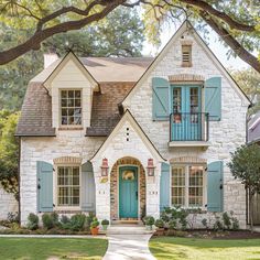 a white brick house with blue shutters on the front door and windows, along with green shutters