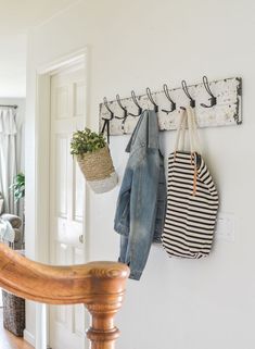 a coat rack with several coats hanging from it's hooks on the wall next to a wooden chair