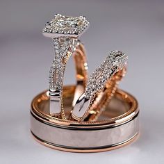 two wedding rings are sitting on top of each other in gold and silver with diamonds