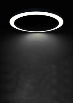 a black and white photo of a circular light fixture in the dark with dim lighting