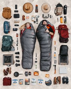 a man and woman laying in sleeping bags surrounded by camping gear, backpacks, hats, and other items