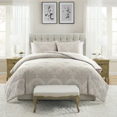 a white bed sitting in a bedroom next to two pictures on the wall above it