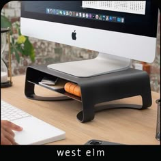 a person sitting at a desk with a computer on it's side and an apple keyboard in front of the monitor