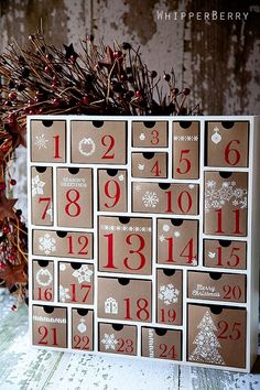 a christmas card with numbers on it sitting next to a planter filled with berries