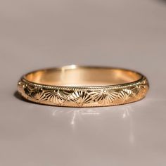 a gold wedding band that has been engraved with flowers and leaves on the inside of it