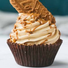 a chocolate cupcake with white frosting and an oreo cookie sticking out of it