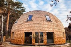 a round wooden building in the middle of a forest